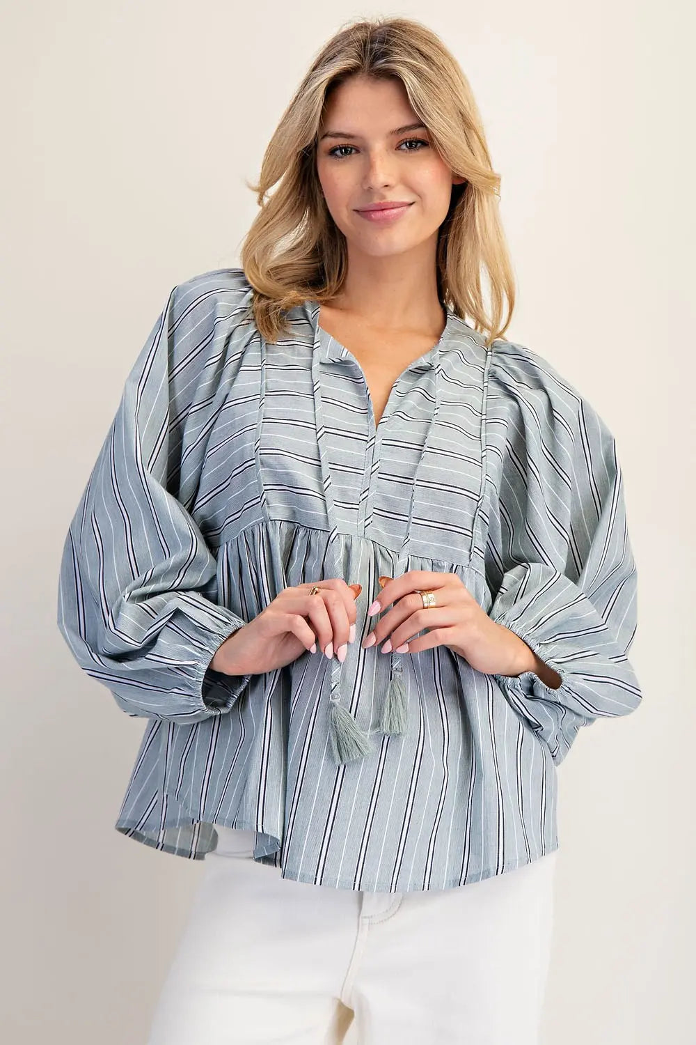 Woman wearing a blue striped blouse against a plain background