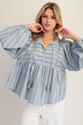 Woman wearing a blue striped blouse against a plain background