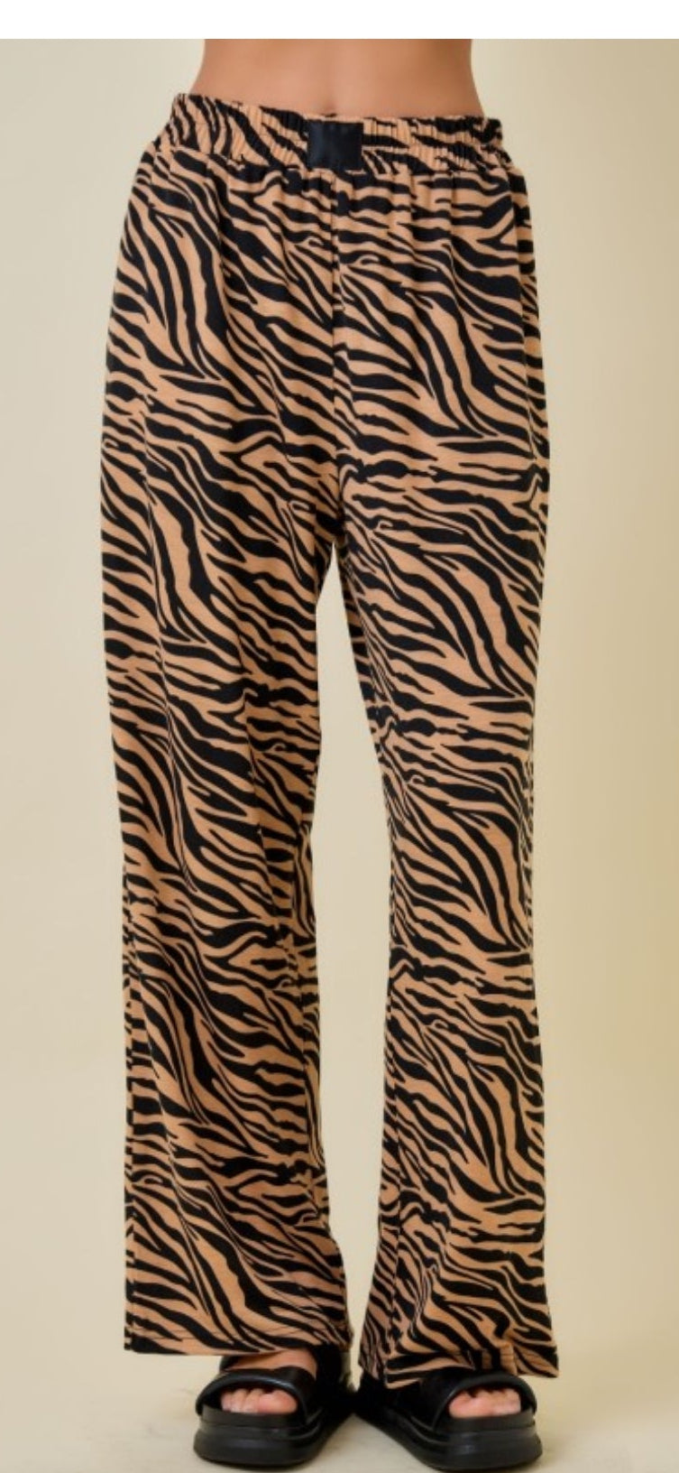 Zebra print pants worn by a person on a beige background